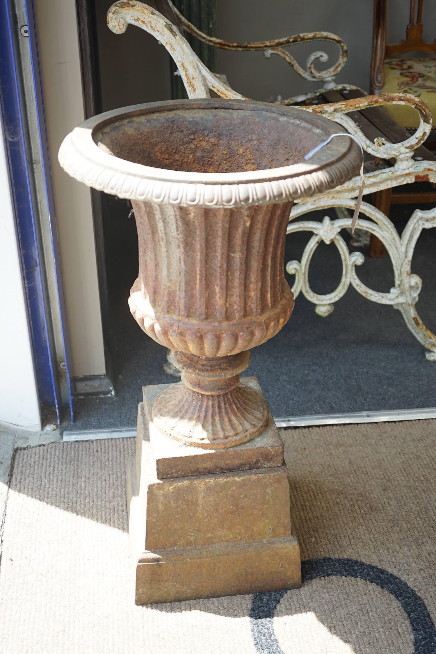 A Victorian style cast iron campana garden urn on a square plinth, diameter 38cm, height 68cm